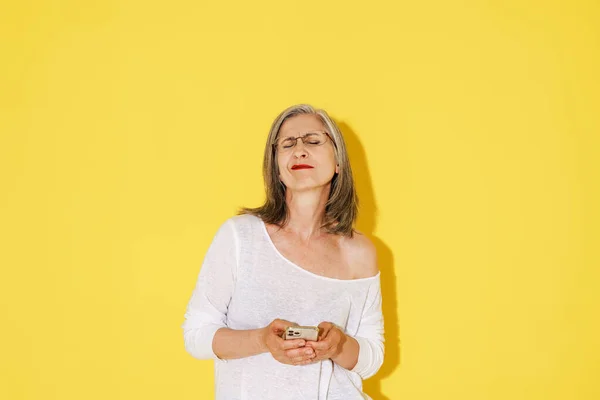 Mature Woman Eyeglasses Grimacing While Using Mobile Phone Isolated Yellow — Stock Photo, Image