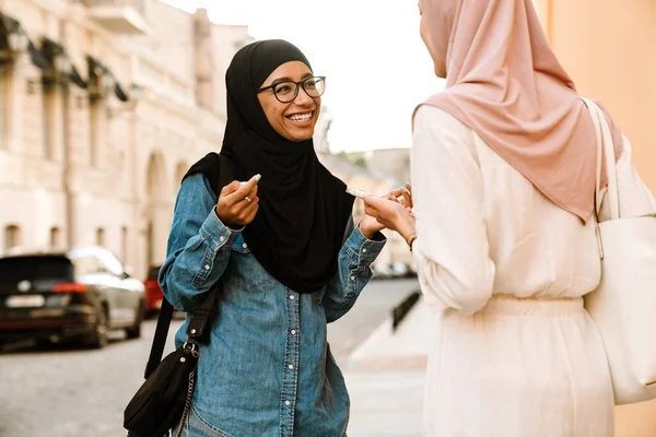 Genç Müslüman kadınlar tesettüre bürünmüş, sokaklarda konuşurken gülümsüyor