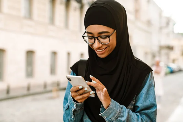 Mladá Muslimka Nosí Hidžáb Úsměvem Pomocí Mobilního Telefonu Ulici — Stock fotografie