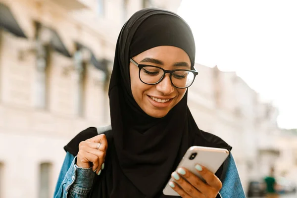 Mladá Muslimka Nosí Hidžáb Úsměvem Pomocí Mobilního Telefonu Ulici — Stock fotografie