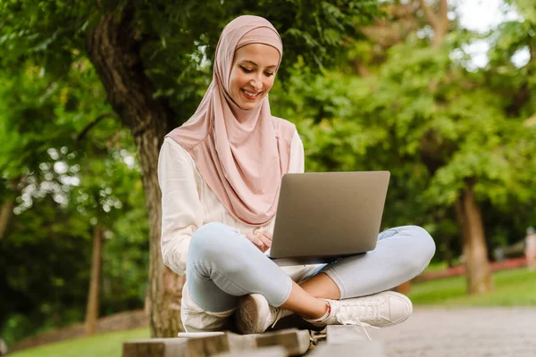 Usmívající Muslimka Středního Věku Sedí Lavičce Venku Pomocí Notebooku — Stock fotografie