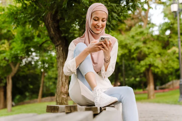 Lächelnde Muslimin Mittleren Alters Sitzt Mit Handy Auf Einer Bank — Stockfoto