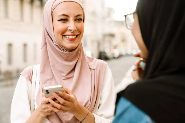 Monirotuinen Musliminaiset Yllään Hijabia Puhuminen Kun Käytät Matkapuhelinta Kaupungin Kadulla — kuvapankkivalokuva