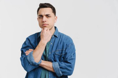 Genç esmer beyaz adam beyaz arka planda izole edilmiş kameraya bakıyor.