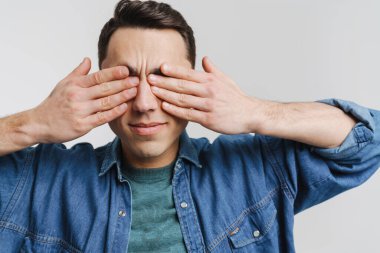 Genç esmer adam beyaz arka planda kulaklarını kapatıyor.