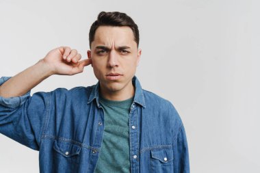 Genç esmer adam kulağını tıkadı ve kaşlarını çattı.