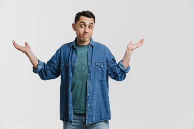 Genç esmer beyaz adam yana bakıyor ve beyaz arka planda izole edilmiş bir telif alanı tutuyor.