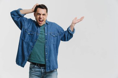 Genç esmer adam beyaz arka planda izole bir şekilde kameraya el kol hareketi yapıp çığlık atıyor.