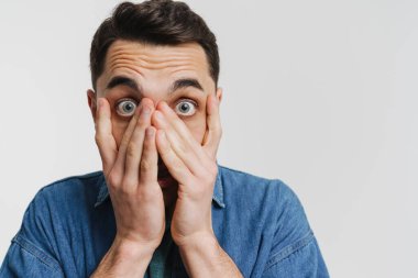 Genç esmer adam beyaz arka planda yüzünü kapatan kot gömlekli.