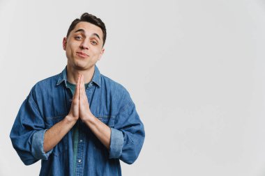 Avuç içlerini bir arada tutan esmer genç adam ve beyaz arka planda soyutlanmış bir şekilde gülümsüyor.