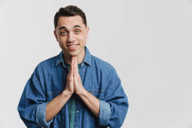 Avuç içlerini bir arada tutan esmer genç adam ve beyaz arka planda soyutlanmış bir şekilde gülümsüyor.