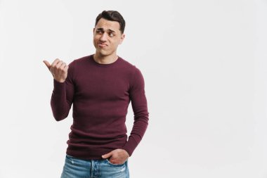 Genç esmer adam somurtuyor ve beyaz arka planda soyutlanmış bir şekilde işaret ediyor.