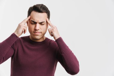 Baş ağrısı olan genç esmer adam beyaz arka planda izole edilmiş şakaklarını ovalıyor.