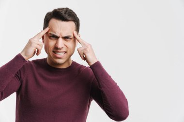 Baş ağrısı olan genç esmer adam beyaz arka planda izole edilmiş şakaklarını ovalıyor.
