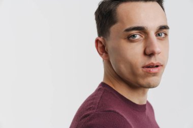 Genç esmer adam poz veriyor ve beyaz arka planda izole edilmiş kameraya bakıyor.