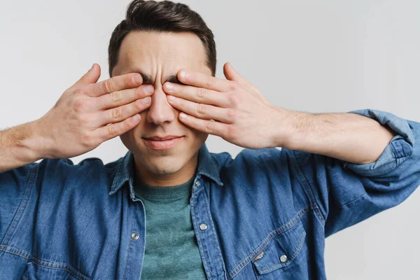 Genç esmer adam beyaz arka planda kulaklarını kapatıyor.