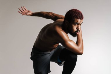 Siyah tişörtsüz sporcu beyaz arka planda tek başına çalışırken koşuyor.