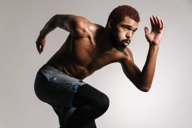 Siyah tişörtsüz sporcu beyaz arka planda tek başına çalışırken koşuyor.