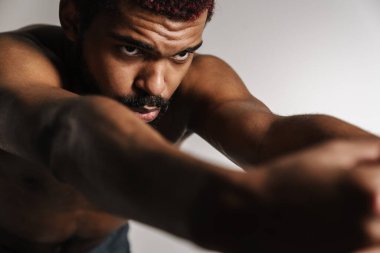 Siyah tişörtsüz sporcu beyaz arka planda tek başına çalışırken egzersiz yapıyor.