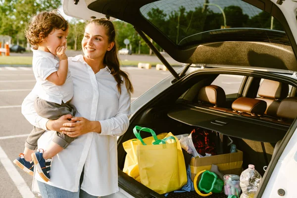 駐車場に車で立っている間 白い女性は笑顔と彼女の息子を保持 — ストック写真