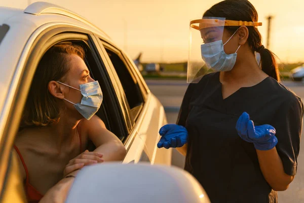 Schwarze Gesundheitshelferin Mit Gesichtsmaske Spricht Mit Weißer Autofahrerin — Stockfoto