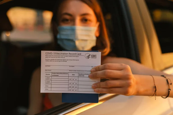 Genç Beyaz Kadın Arabada Otururken Kovid Aşı Kartı Gösteriyor — Stok fotoğraf