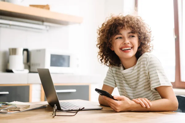 Sonriente Mujer Rizada Que Trabaja Con Ordenador Portátil Teléfono Celular — Foto de Stock