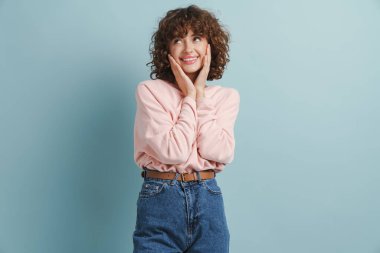 Genç kızıl mutlu kadın gülüyor ve mavi arka planda bir kenara bakıyor.