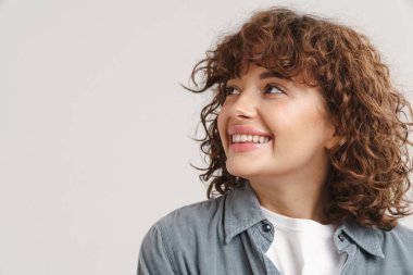 Genç kızıl mutlu kadın gülümsüyor ve beyaz arka planda izole edilmiş kameraya bakıyor.