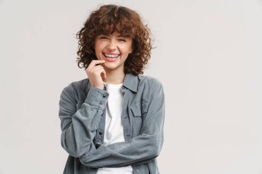 Genç kızıl mutlu kadın gülüyor ve beyaz arka planda izole edilmiş kameraya bakıyor.