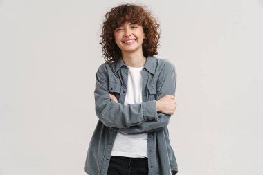 Genç kızıl mutlu kadın gülümsüyor ve beyaz arka planda izole edilmiş kameraya bakıyor.