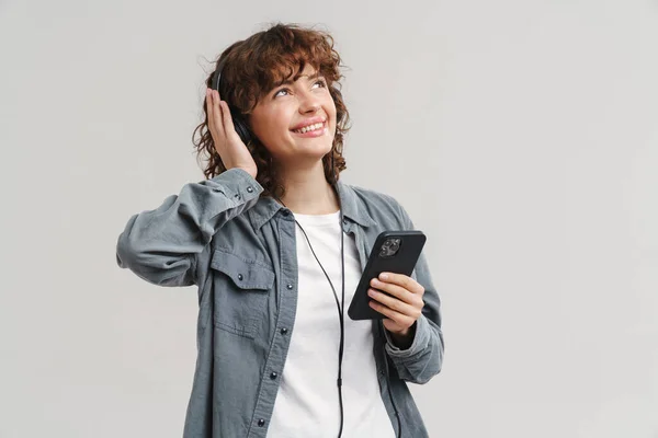 Νεαρή Κοκκινομάλλα Χαρούμενη Γυναίκα Ακούγοντας Μουσική Ακουστικά Και Κινητό Τηλέφωνο — Φωτογραφία Αρχείου