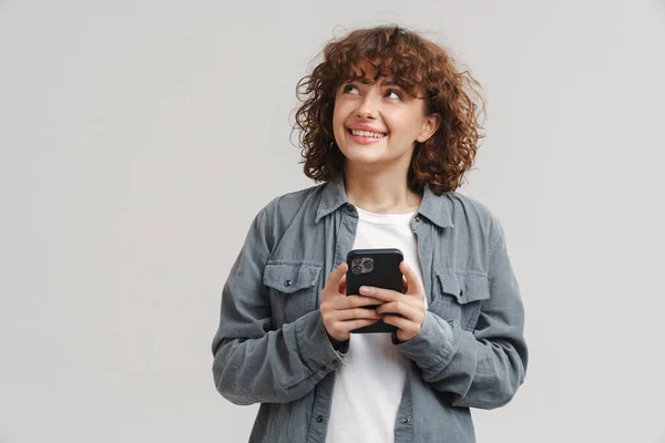 Wanita Muda Yang Gembira Tersenyum Sambil Menggunakan Ponsel Yang Terisolasi — Stok Foto