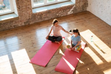 Down sendromlu genç bir kadın içeride koçla yoga dersi alıyor.