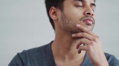 Evde çalışan, tişört giyen yakışıklı Hintli adam.