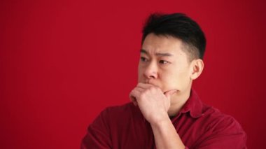 Kırmızı stüdyoda gömlek giyen ciddi bir Asyalı.