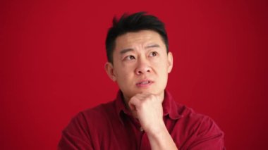 Ciddi bir Asyalı adamın kırmızı stüdyoda bir fikri var.