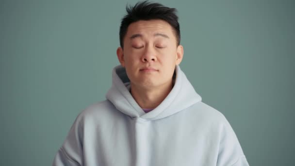 Alegre Homem Asiático Vestindo Capuz Balançando Positivamente Cabeça Estúdio Azul — Vídeo de Stock