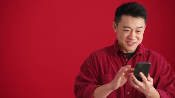 Удивлённый Азиат Рубашке Смотрящий Телефон Показывающий Разные Жесты Красной Студии — стоковое видео
