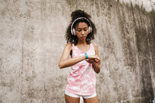 Giovane Sportiva Nera Cuffia Guardando Suo Smartwatch Mentre Piedi Vicino — Foto Stock