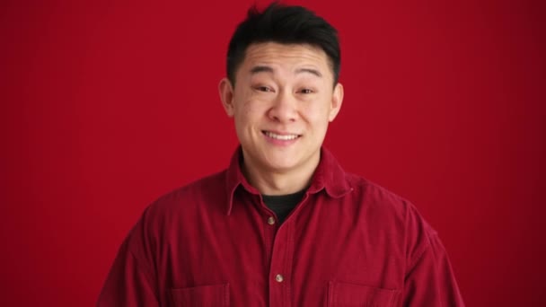 Kırmızı Stüdyoda Gülümseyen Asyalı Gömlekli Bir Adam Baş Parmağıyla Jest — Stok video