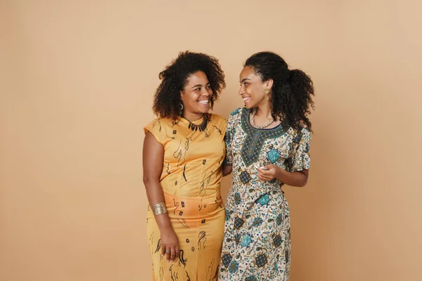 Молодые Черные Две Женщины Обнимаются Улыбаются Камеру Изолированы Бежевом Фоне — стоковое фото