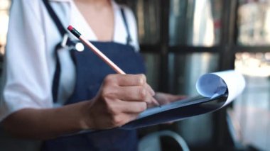 Bayan yönetici bir kafede bulunan malların bir listesini yazar.