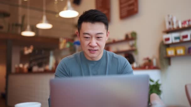 Счастливый Азиатский Молодой Человек Работающий Ноутбуком Кафе — стоковое видео