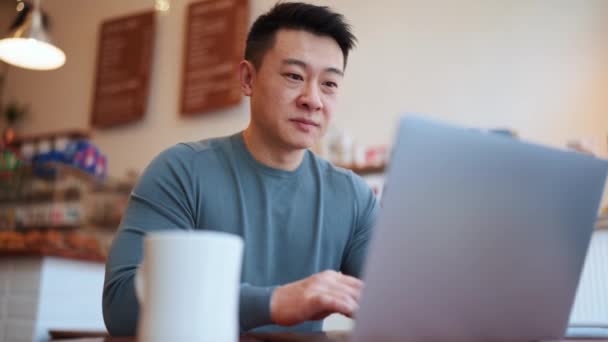 Positiver Asiatischer Junger Mann Arbeitet Mit Laptop Café — Stockvideo