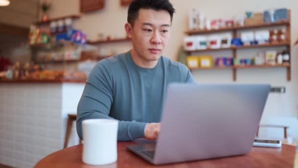 Серьезный Азиатский Молодой Человек Работающий Ноутбуком Кафе — стоковое видео
