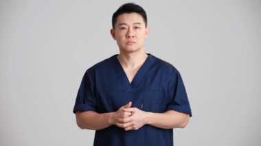 Konsantre Asyalı doktor gri stüdyodaki bir şeye katılıyor.