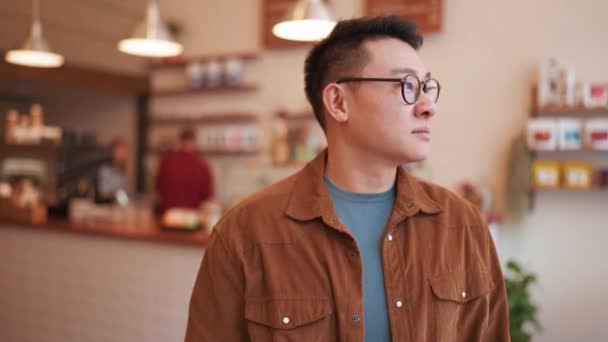 Veselý Asijský Mladý Muž Nosí Brýle Při Pohledu Kameru Kavárně — Stock video