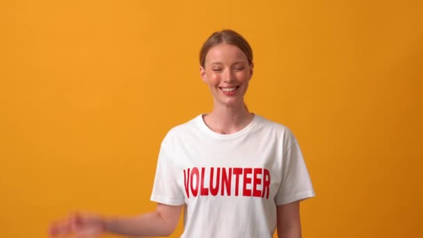 微笑的女性志愿者看着橙色工作室里的相机 — 图库视频影像