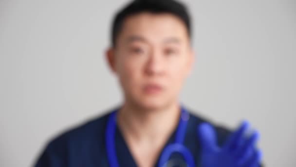 Poważny Azjatycki Lekarz Pstrykający Palcami Przed Kamerą Szarym Studio — Wideo stockowe